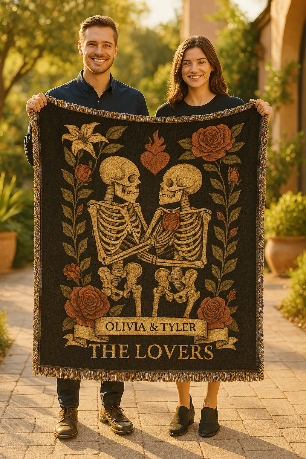 Two people holding a blanket with skeletons and roses design, featuring names 'Olivia & Tyler' and 'The Lovers'.