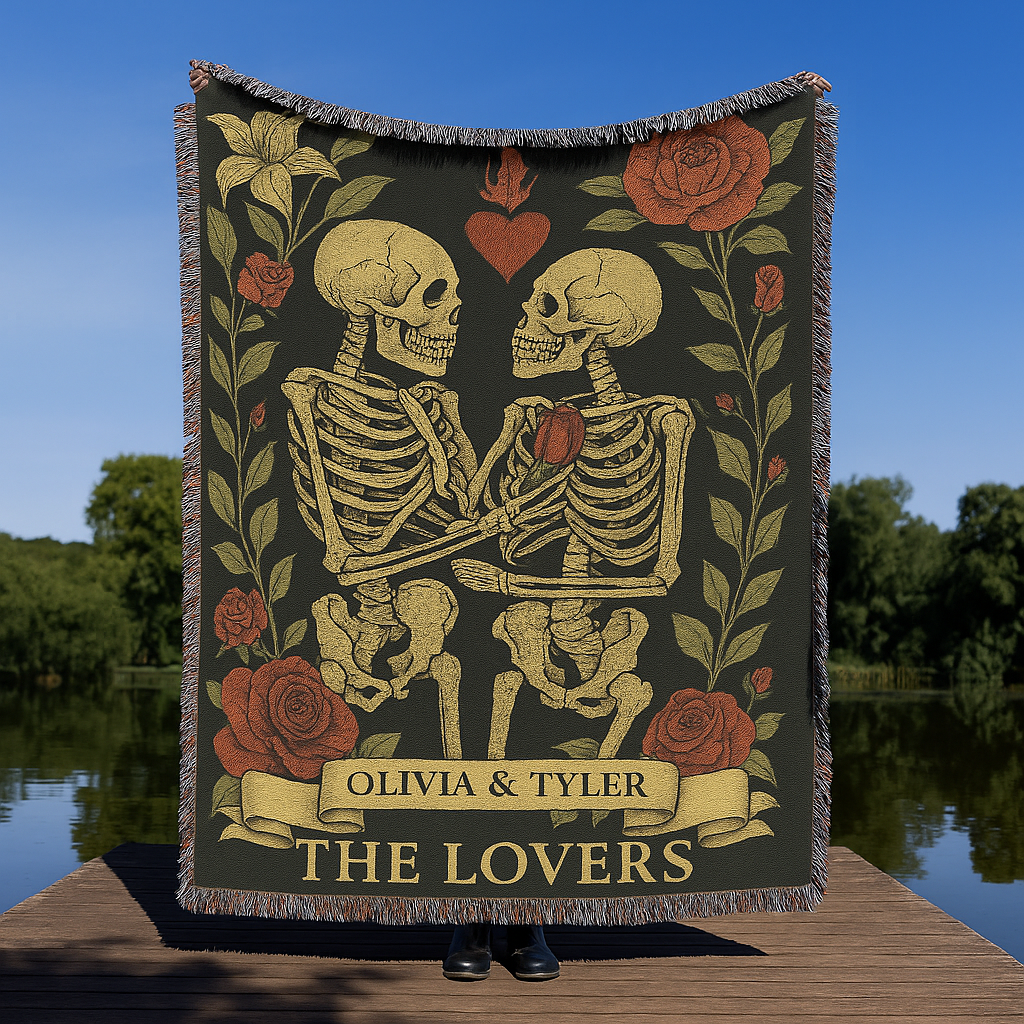 Blanket with skeletons holding a heart and floral design, displayed outdoors.